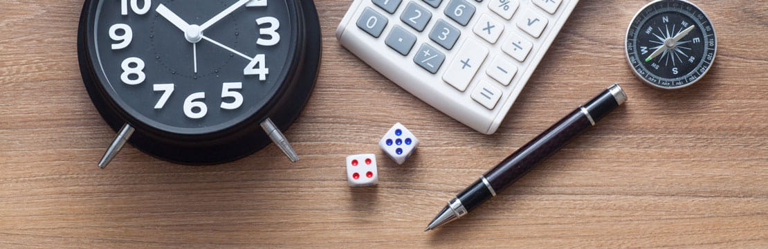 Image containing an alarm clock, a calculator, a compass, a pen and two dice.